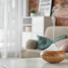 Difusor de aceites esenciales liberando vapor aromático. Descubre cómo usar los aceites esenciales para perfumar la casa y crear un ambiente acogedor.