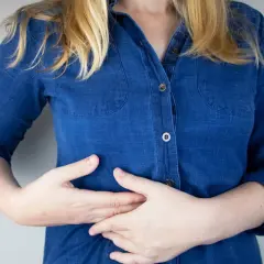 Persona con las manos en el abdomen, sintiendo pinchazos en el costado derecho debajo de las costillas.