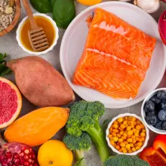 Salmón, batatas, brócoli, arándanos y semillas son algunos de los alimentos con vitamina B que se ven en la imagen.