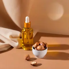 Aceite de argán en frasco y frutos secos en cuenco. Descubre las maravillosas propiedades del aceite de argán para tu piel y cabello.