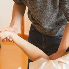 Terapeuta examina la muñeca de un paciente. ¿Puedo ir a trabajar con un esguince de muñeca?