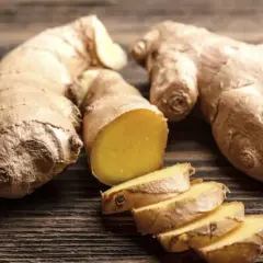Raíces de jengibre enteras y cortadas en rodajas, mostrando su interior amarillo vibrante. Un tesoro natural con innumerables propiedades del jengibre.