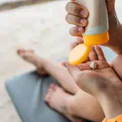 Manos aplicando crema solar en la palma. ¡Revisa la caducidad crema solar antes de usarla para proteger tu piel!