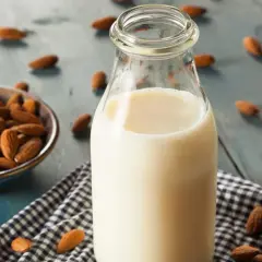 Botella de leche de almendras junto a un cuenco con almendras. Descubre las leche de almendras propiedades y beneficios.