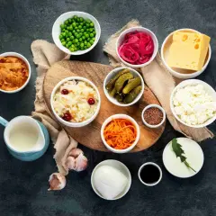 Variedad de 20 alimentos probióticos: kimchi, chucrut, pepinillos, yogur, queso, cebolla morada encurtida, zanahoria rallada, guisantes, ajo, semillas de lino y más.