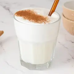 Vaso de leche espumosa con canela espolvoreada, ideal para relajarse.