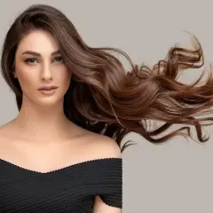 Mujer con cabello castaño ondulado y largo, con un vestido negro. ¿Buscas cómo quitar tinte?
