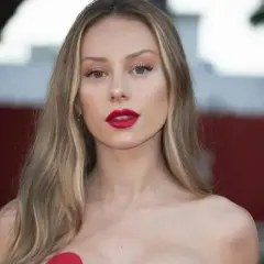 Mujer con labios rojos y cabello largo con mechas rubias naturales que brillan bajo la luz.