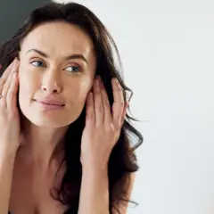 Mujer se toca la cara, preocupada por la retención de líquidos en la cara.