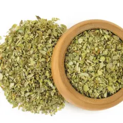 Hierbas secas de mejorana en un cuenco de madera y esparcidas. Descubre las mejorana propiedades para tu cocina y bienestar.