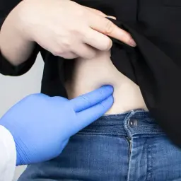 Médico examina abdomen, buscando la causa del dolor costado derecho.