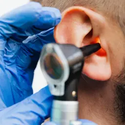 Médico examina oído con otoscopio. Si tienes dolor de oído, ¿qué tomar? Consulta a un profesional.