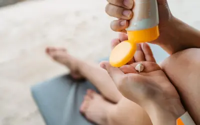 Manos aplicando crema solar en la palma. ¡Revisa la caducidad crema solar antes de usarla para proteger tu piel!