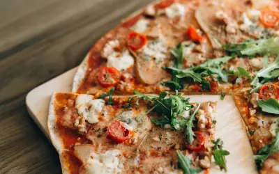 Pizza saludable para dieta, con rúcula fresca, tomates cherry y queso derretido sobre una base crujiente.