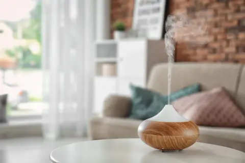 Difusor de aceites esenciales liberando vapor aromático. Descubre cómo usar los aceites esenciales para perfumar la casa y crear un ambiente acogedor.