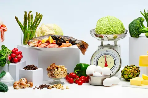 Variedad de alimentos frescos: pescado, mariscos, verduras, huevos, frutos secos y queso. Ejemplos de carbohidratos y proteínas para una dieta equilibrada.