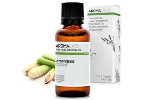 Aceite esencial de Lemongrass, ideal como aceite repelente de mosquitos. Botella de vidrio ámbar con etiqueta blanca y tallos de hierba limón.