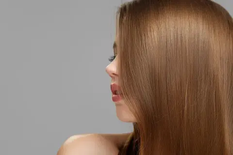 Perfil de mujer con cabello liso y brillante en tonos de castaño, destacando su naturalidad y salud.