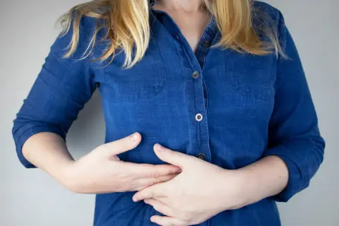 Persona con las manos en el abdomen, sintiendo pinchazos en el costado derecho debajo de las costillas.