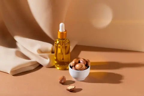 Aceite de argán en frasco y frutos secos en cuenco. Descubre las maravillosas propiedades del aceite de argán para tu piel y cabello.
