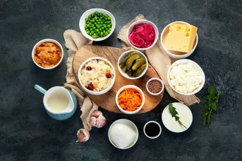 Variedad de 20 alimentos probióticos: kimchi, chucrut, pepinillos, yogur, queso, cebolla morada encurtida, zanahoria rallada, guisantes, ajo, semillas de lino y más.