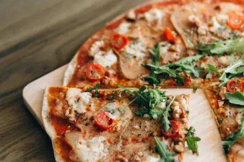Pizza saludable para dieta, con rúcula fresca, tomates cherry y queso derretido sobre una base crujiente.
