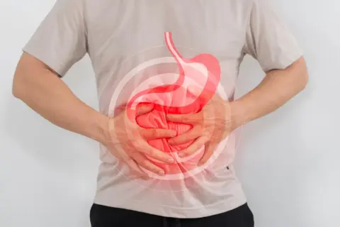 Hombre con dolor de estómago, buscando qué tomar para el reflujo. Imagen ilustra malestar digestivo.