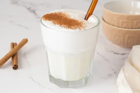 Vaso de leche espumosa con canela espolvoreada, ideal para relajarse.