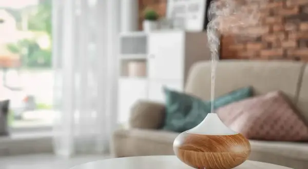 Difusor de aceites esenciales liberando vapor aromático. Descubre cómo usar los aceites esenciales para perfumar la casa y crear un ambiente acogedor.