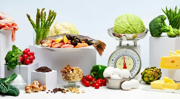 Variedad de alimentos frescos: pescado, mariscos, verduras, huevos, frutos secos y queso. Ejemplos de carbohidratos y proteínas para una dieta equilibrada.