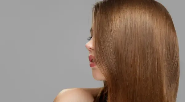 Perfil de mujer con cabello liso y brillante en tonos de castaño, destacando su naturalidad y salud.