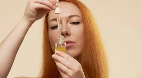 Mujer pelirroja aplica serum vitamina c para que sirve, iluminando su piel.