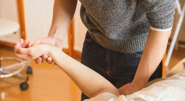 Terapeuta examina la muñeca de un paciente. ¿Puedo ir a trabajar con un esguince de muñeca?