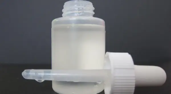 Frasco con gotero y líquido blanco lechoso, listo para usar como suero casero.
