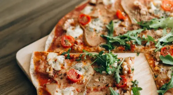 Pizza saludable para dieta, con rúcula fresca, tomates cherry y queso derretido sobre una base crujiente.