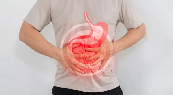 Hombre con dolor de estómago, buscando qué tomar para el reflujo. Imagen ilustra malestar digestivo.