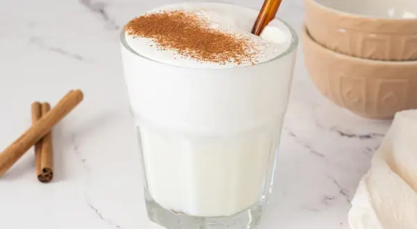 Vaso de leche espumosa con canela espolvoreada, ideal para relajarse.