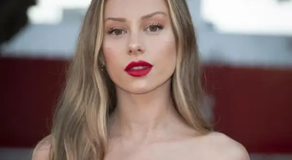 Mujer con labios rojos y cabello largo con mechas rubias naturales que brillan bajo la luz.