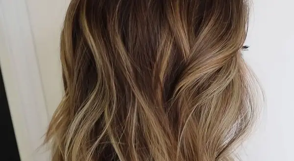 Cabello ondulado con un degradado de rubio a raíz castaña, con reflejos dorados que le dan luz.