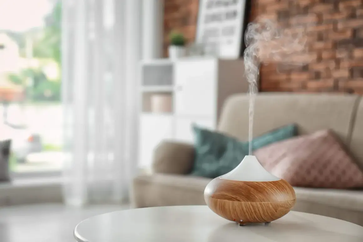 Difusor de aceites esenciales liberando vapor aromático. Descubre cómo usar los aceites esenciales para perfumar la casa y crear un ambiente acogedor.