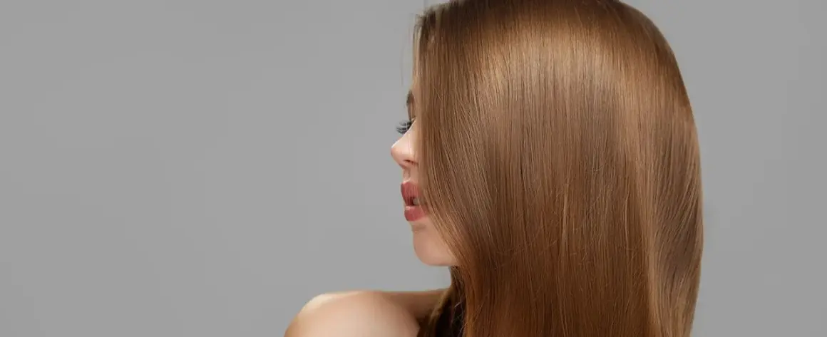 Perfil de mujer con cabello liso y brillante en tonos de castaño, destacando su naturalidad y salud.