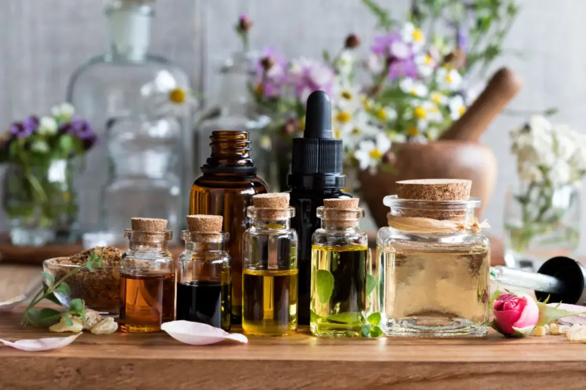 Frascos de vidrio con aceites esenciales para aromaterapia, rodeados de flores y hierbas.