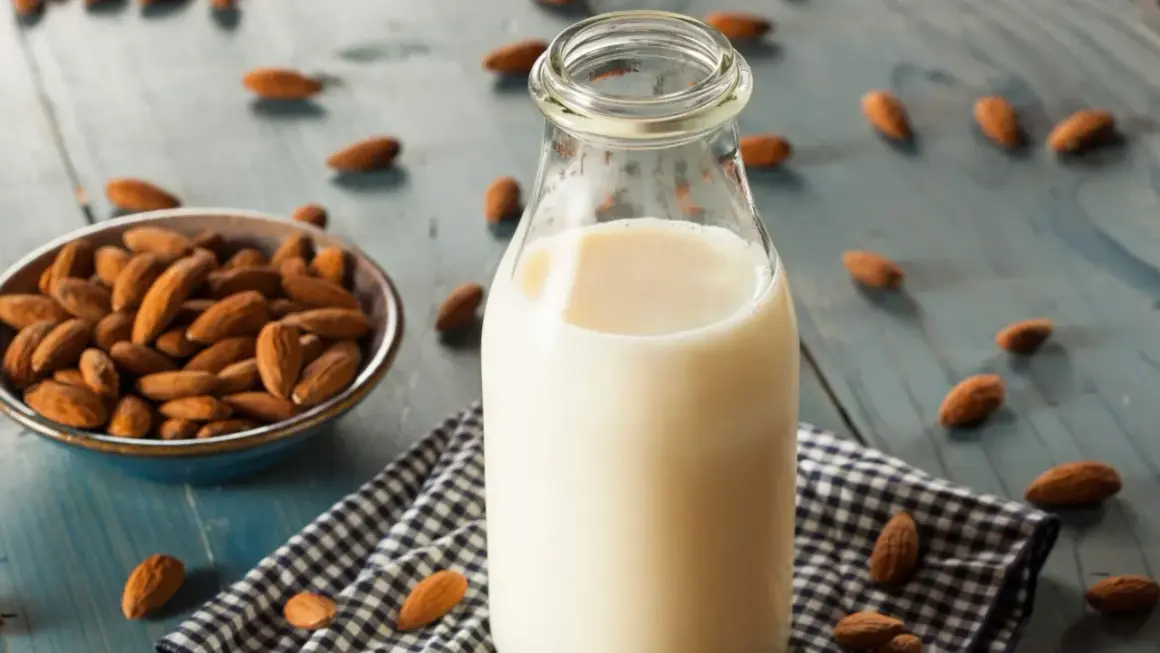 Botella de leche de almendras junto a un cuenco con almendras. Descubre las leche de almendras propiedades y beneficios.