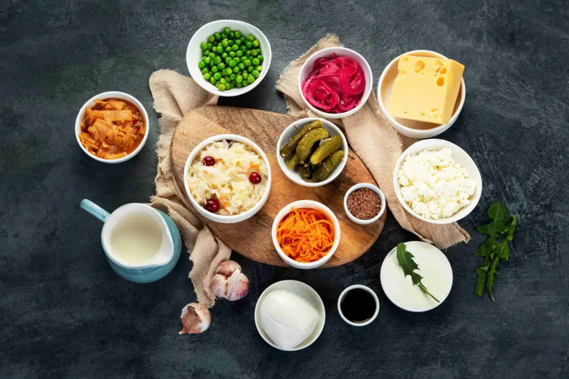 Variedad de 20 alimentos probióticos: kimchi, chucrut, pepinillos, yogur, queso, cebolla morada encurtida, zanahoria rallada, guisantes, ajo, semillas de lino y más.