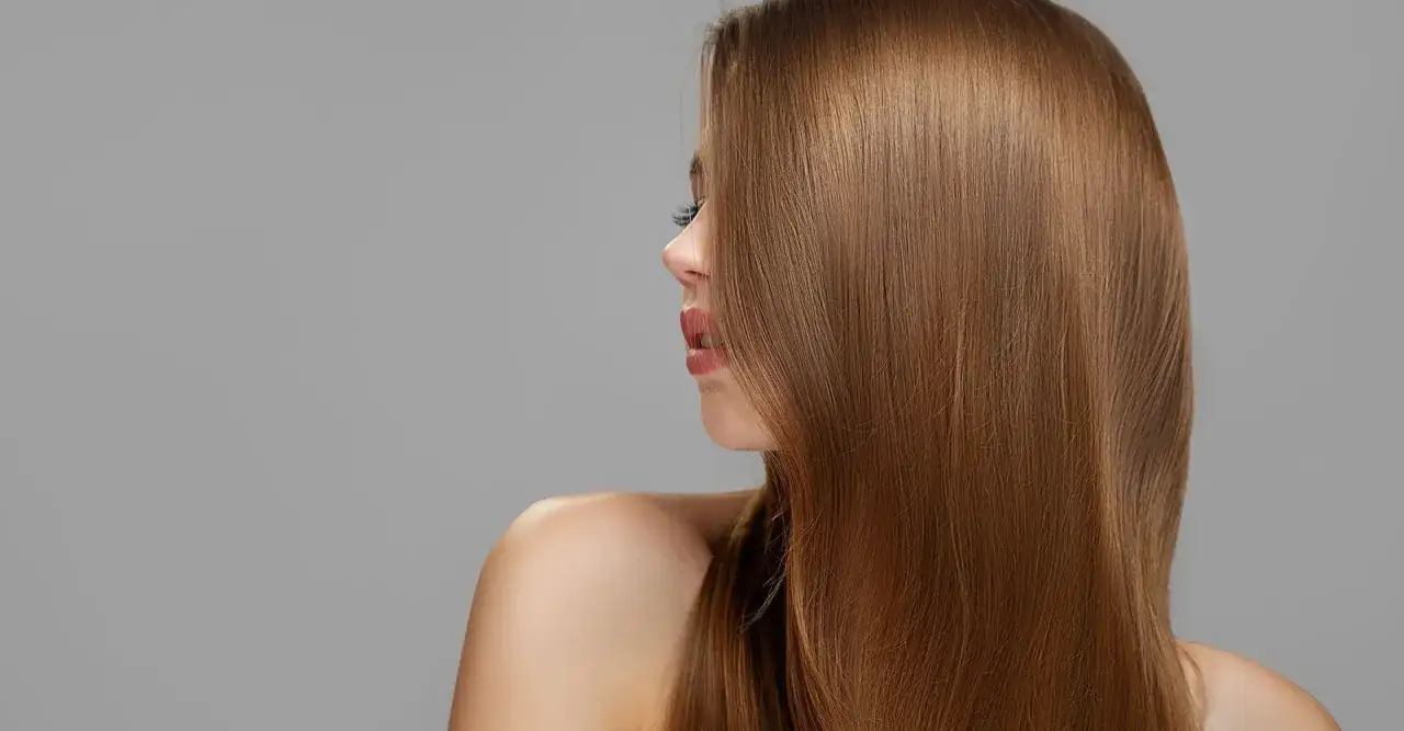 Cabello liso y sedoso en hermosos tonos de castaño, cayendo sobre el hombro de una mujer.