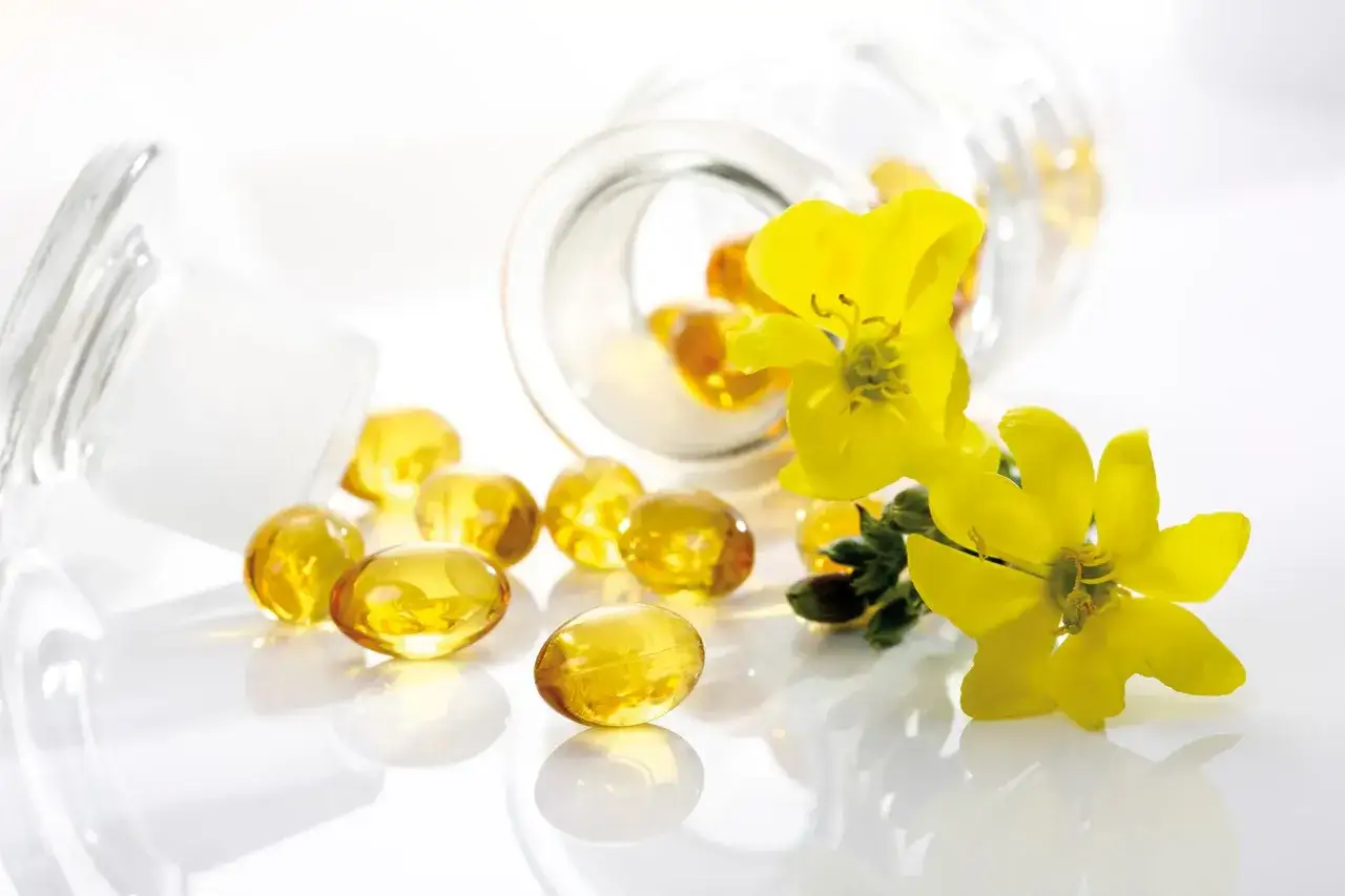 C&aacute;psulas de aceite de onagra junto a flores amarillas, ideal para la dosis de menopausia.