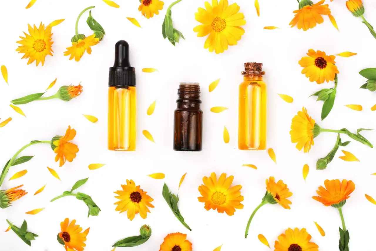 Aceite de cal&eacute;ndula para que sirve: extracto natural para cuidado de la piel, rodeado de flores y p&eacute;talos de cal&eacute;ndula.