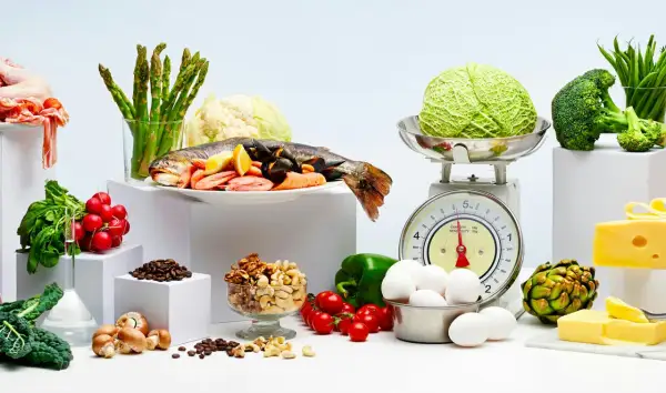 Variedad de alimentos frescos: pescado, mariscos, verduras, huevos, frutos secos y queso. Ejemplos de carbohidratos y proteínas para una dieta equilibrada.