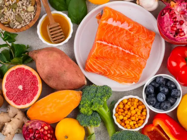 Salmón, batatas, brócoli, arándanos y semillas son algunos de los alimentos con vitamina B que se ven en la imagen.