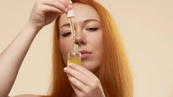 Mujer pelirroja aplica serum vitamina c para que sirve, iluminando su piel.
